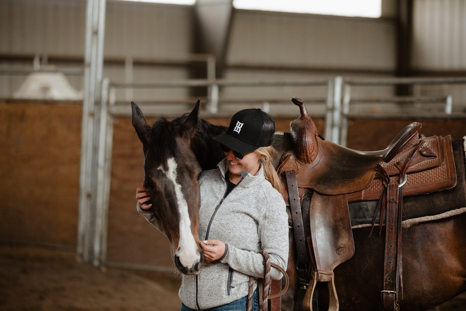 Woman wearing BEX Black Steel cap with her horse in the arena, Western saddle
